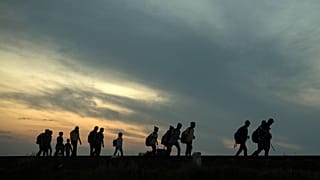 مجموعة من اللاجئين يسيرون على طول خطوط السكك الحديدية بالقرب من مدينة روسكي