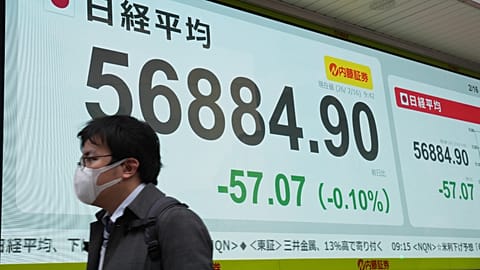 Japonya'nın Nikkei endeksini gösteren bir ekranın önünde yürüyen bir kişi, Tokyo, 16 Şubat 2026