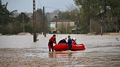 Feuerwehrleute schieben in La Réole ein Schlauchboot über eine überflutete Straße. Sturmtief Nils setzt Westfrankreich großflächig unter Wasser.