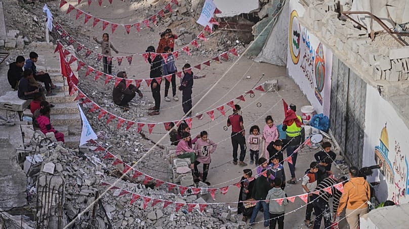 فلسطينيون يعلّقون زينة رمضان إلى جانب أنقاض منازل مدمّرة في خان يونس جنوب قطاع غزة، بتاريخ 15 فبراير 2026.