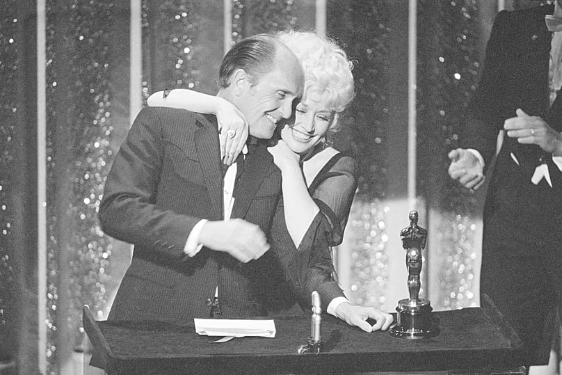 Robert Duvall is embraced by singer Dolly Parton upon his receipt of the best actor award for his performance in "Tender Mercies" on 9 April 1984.