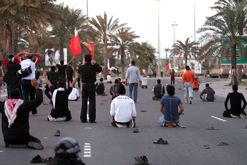  جلس متظاهرون بحرينيون كانوا يسيرون باتجاه دوار اللؤلؤة في الشارع أمام دبابات الجيش يوم الجمعة 18 فبراير/شباط 2011 في المنامة، البحرين.