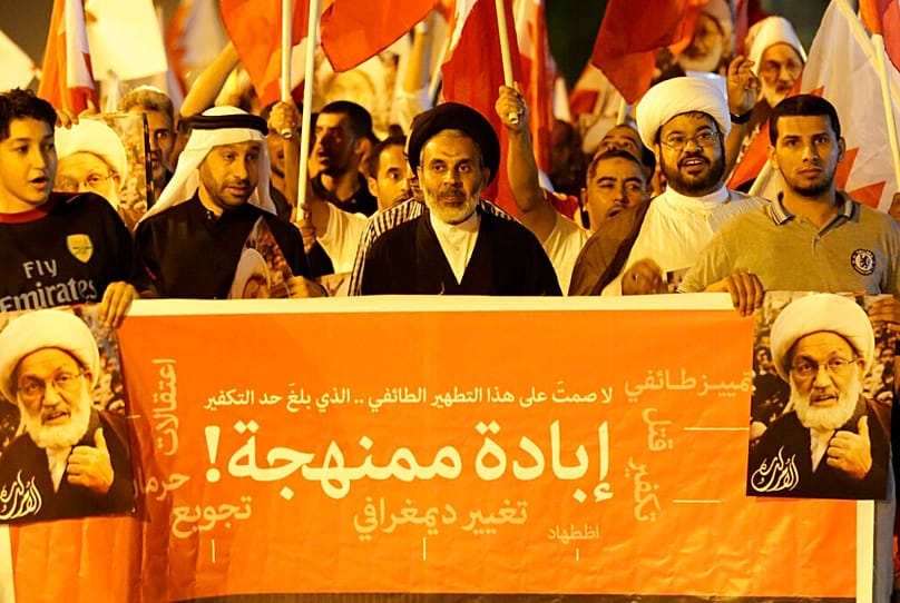 رفع متظاهرون بحرينيون مناهضون للحكومة الأعلام الوطنية وحملوا صوراً للشيخ عيسى قاسم، خلال مظاهرة في مدينة سار، البحرين، يوم السبت 19 يوليو/تموز 2014. 