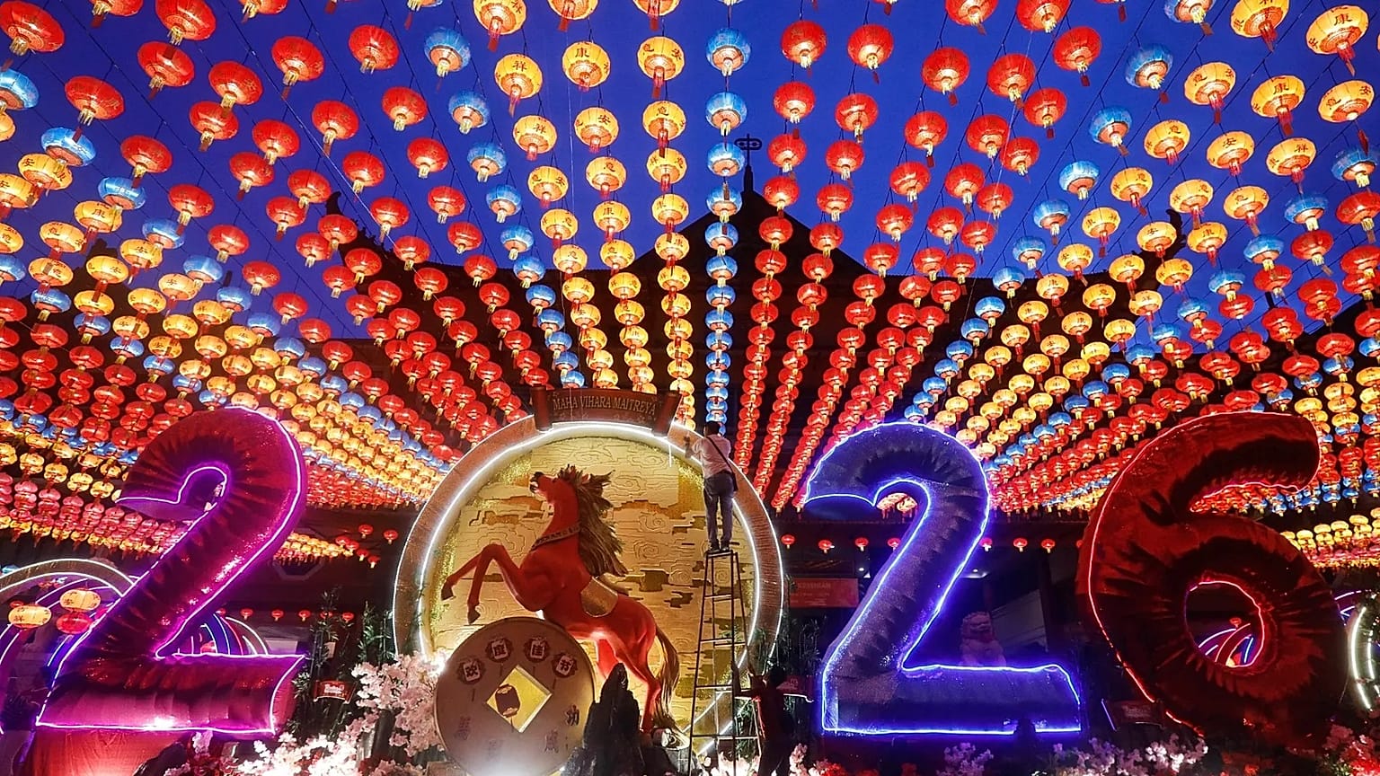 A man looks out from a window decorated with "2026" and festive Lunar New Year ornaments in Beijing, China, Monday, Feb. 16, 2026. (AP Photo/Vincent Thian)