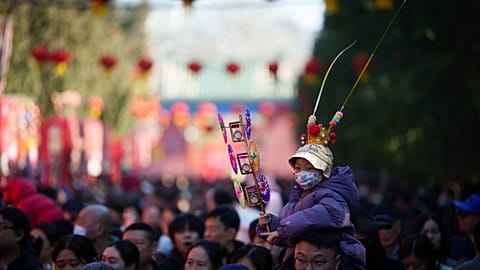 Un niño con gorro festivo se sienta sobre los hombros de un adulto en una feria del templo por el Año Nuevo Lunar en Pekín, China, el 17 feb. 2026.