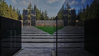 Bir adam, 16 Şubat 2026 Pazartesi günü Atina'nın Kaisariani banliyösünde bulunan Kaisariani Atış Poligonundaki anma alanında yürüyor.