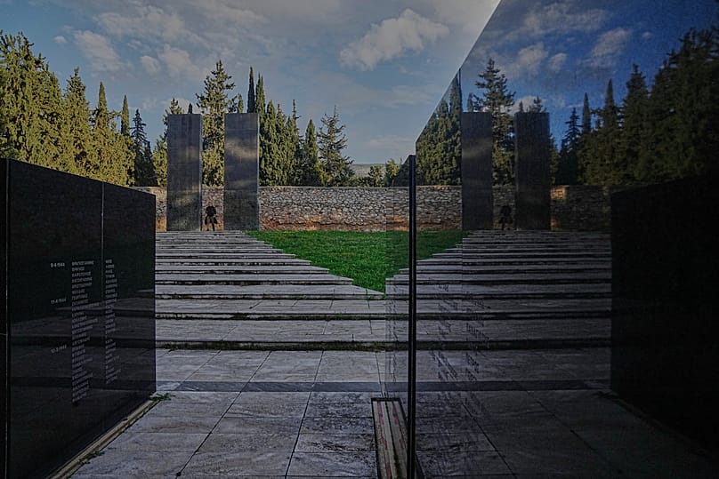 Mężczyzna przechodzi przez teren miejsca pamięci na strzelnicy w Kaisariani, na przedmieściach Aten, w poniedziałek 16 lutego 2026 r.