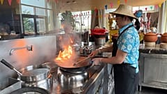 Thai chef in action, cooking with flames in Doha.