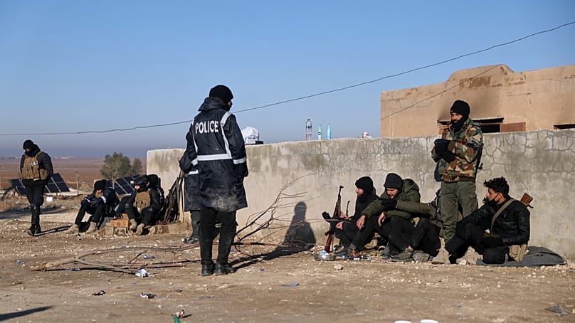 Syrian government troops stand guard at the entrance to the Al-Hol camp in northeastern Syria's Hasakeh province, Syria, Wednesday, Jan. 21, 2026,