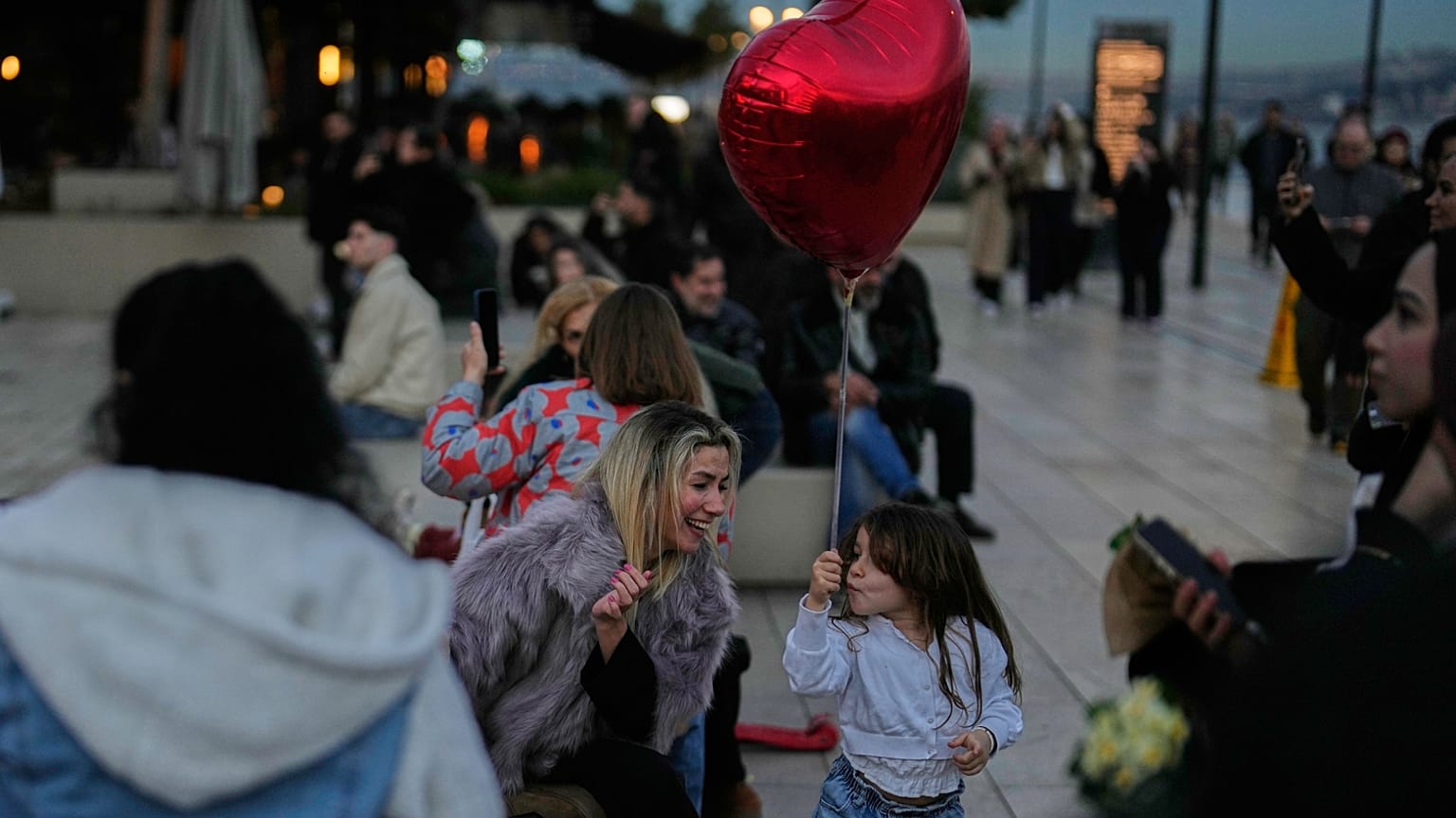 İstanbul'da Sevgililer Günü'nde bir kadın, elinde kırmızı kalp şeklinde bir balon tutan kızıyla oynuyor, 14 Şubat 2026.