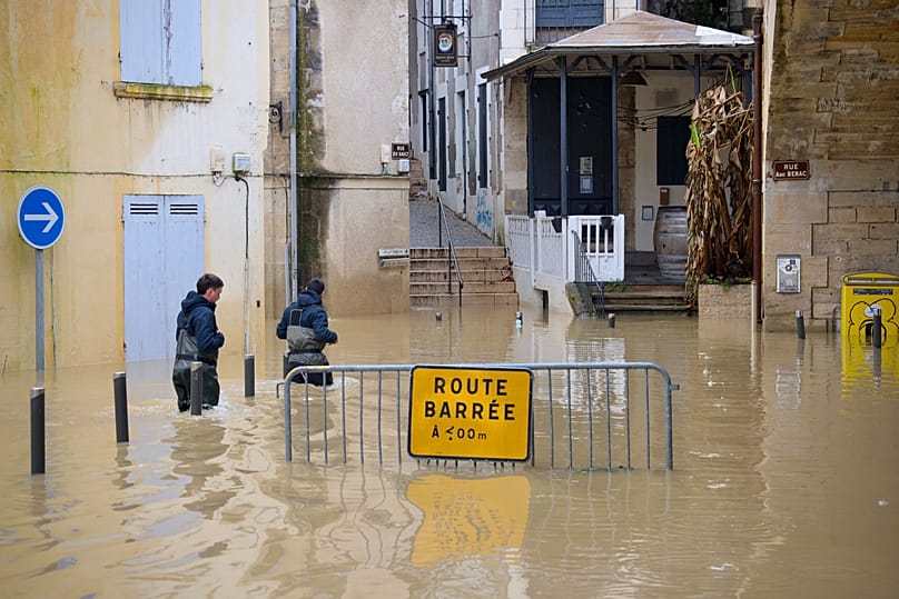 City workers walk through a flooded street of La Reole, western France amid storm Nils, Monday, Feb. 16, 2026.
