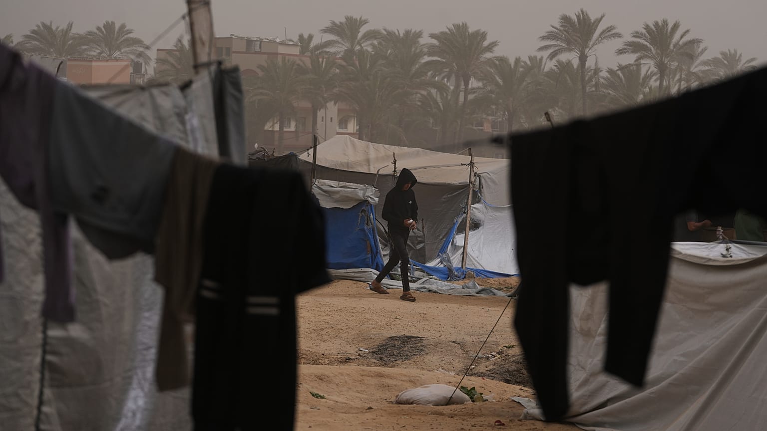 شاب فلسطيني يسير في مخيم مؤقت للنازحين، خلال عاصفة ترابية في منطقة الزوايدة وسط قطاع غزة، السبت 14 فبراير/شباط 2026.