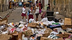 Pessoas tapam o nariz ao passar por uma rua com lixo em Havana