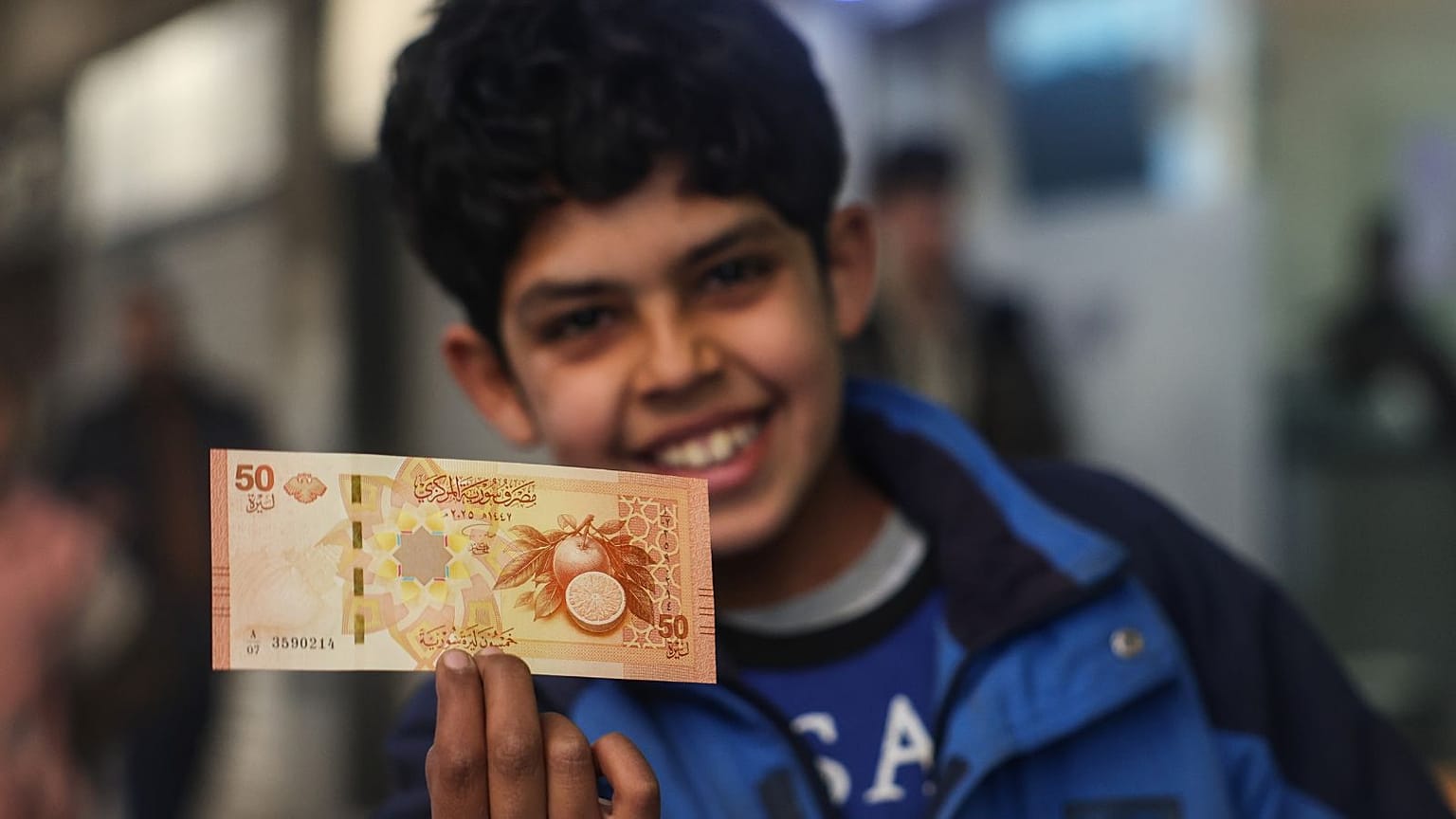 کودکی خوشحال سوری اسکناس‌ جدید ۵۰ لیری را نشان می‌دهد