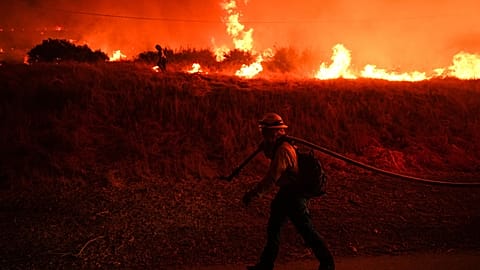 FILE - A firefighter monitors flames caused by the Hughes Fire along Castaic Lake in Castaic, Calif., Jan. 22, 2025. 