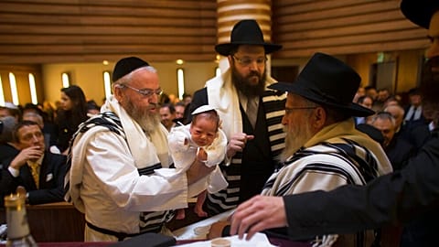  Mohel Manachem Fleischmann, left, holds baby Mendl Teichtal after the circumcision ceremony at the Chabad Lubawitsch Orthodox Jewish synagogue in Berlin, Germany. March 2013