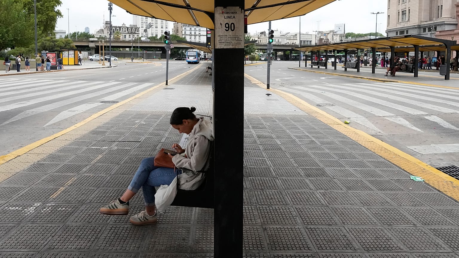 Una mujer sentada en una parada de autobús vacía debido a una huelga sindical contra el proyecto de ley de reforma laboral propuesto por el presidente Javier Milei 