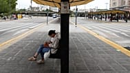 Una mujer sentada en una parada de autobús vacía debido a una huelga sindical contra el proyecto de ley de reforma laboral propuesto por el presidente Javier Milei 