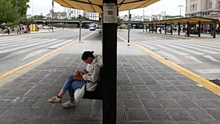 Una mujer sentada en una parada de autobús vacía debido a una huelga sindical contra el proyecto de ley de reforma laboral propuesto por el presidente Javier Milei 