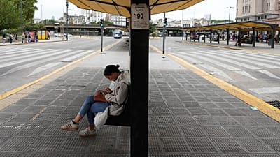 Una mujer sentada en una parada de autobús vacía debido a una huelga sindical contra el proyecto de ley de reforma laboral propuesto por el presidente Javier Milei 