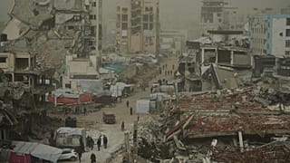 فلسطينيون يسيرون على طول شارع محاط بمباني دمرت في العمليات الجوية والبرية الإسرائيلية خلال عاصفة ترابية في مدينة غزة, السبت, فبراير. 14, 2026.