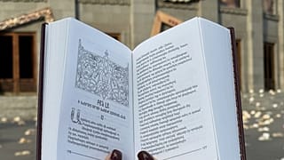 Книга Григора Нарекаци - армянского поэта, философа и богослова, святого Армянской апостольской церкви и Католической церкви, на фоне Оперы города Еревана