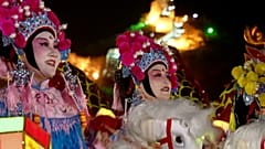 Frauen in traditionellen Kostümen führen an der Chinesischen Mauer eine Show mit Attrappenpferden auf.