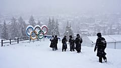 Menschen laufen während der Olympischen Winterspiele 2026 in Cortina d'Ampezzo, Italien, am Donnerstag, 19. Februar 2026, an den olympischen Ringen im Gleitzentrum vorbei. 