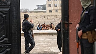 يجلس أعضاء سابقون في قوات سوريا الديمقراطية على الرصيف بانتظار تسجيل أسمائهم في مركز مصالحة تديره الحكومة للحصول على وثائق رسمية تثبت تركهم للجماعة وتجنب المزيد من الملاحقة ال