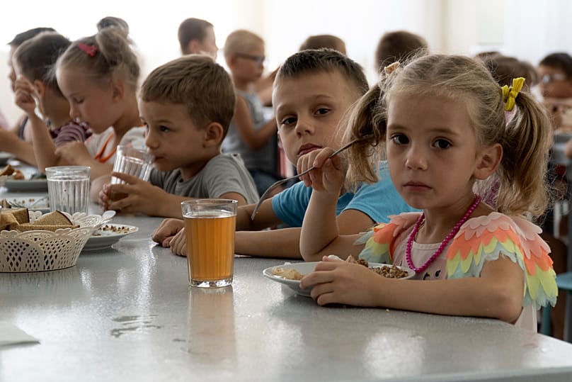 Ukrainian kids from an orphanage in Donetsk region, eat a meal at a camp in Zolotaya Kosa, the settlement on the Sea of Azov, Rostov region, southwestern Russia, July 8, 2022