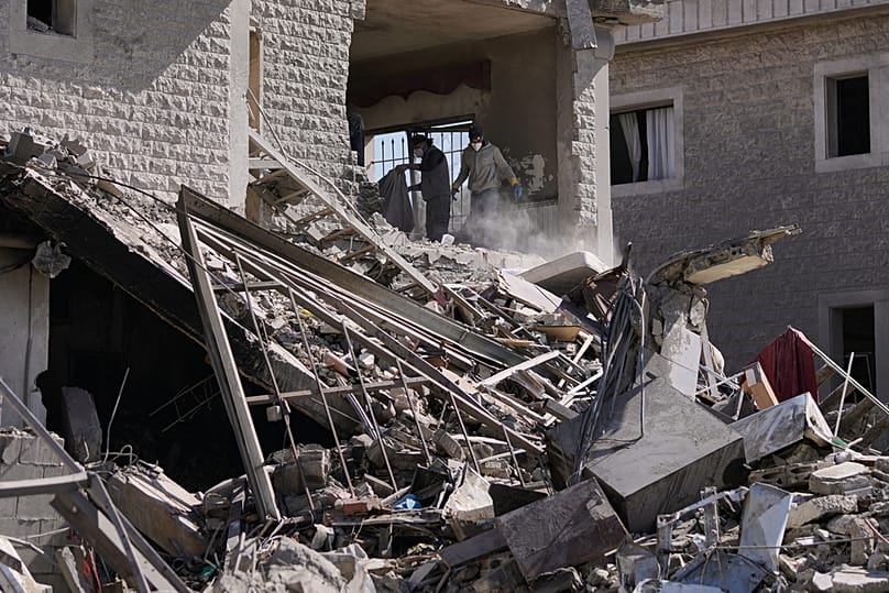 People collect the remains of their belongings from a building destroyed in an Israeli strike in the village of Bednayel in eastern Lebanon, Saturday, Feb. 21, 2026