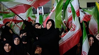 Women wave Iranian flags during a state-organized memorial ceremony for those killed during January's anti-government protests, at the Imam Khomeini Grand Mosque in Tehran.