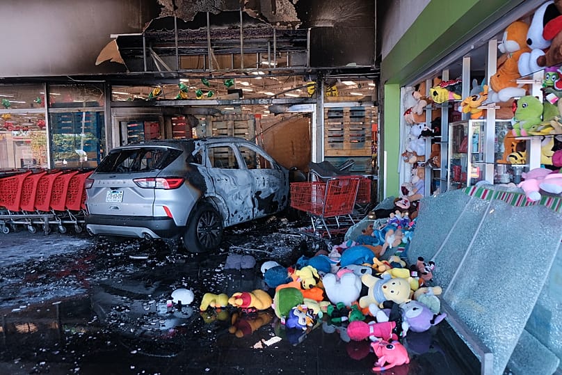 A charred vehicle sits at a damaged supermarket in Guadalajara, Jalisco state, Mexico, Sunday, Feb. 22, 2026, after the death of cartel leader "El Mencho."