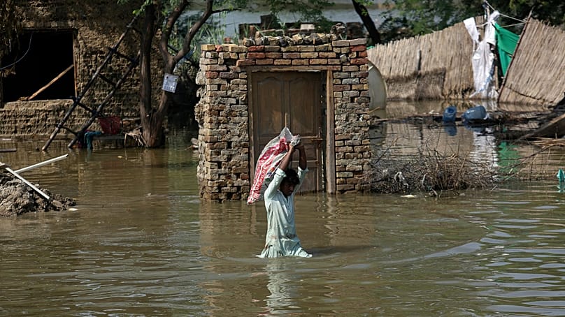 ARCHIVES - Un homme transporte les effets encore utilisables récupérés dans sa maison inondée, en traversant une zone submergée dans le district de Shikarpur, dans la province du Sindh, au Pakistan, le mercredi 31 août 2022. 