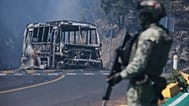 A soldier stands guard by a charred vehicle after it was set on fire, in Cointzio, Michoacán state, following the death of the leader of the Jalisco New Generation Cartel