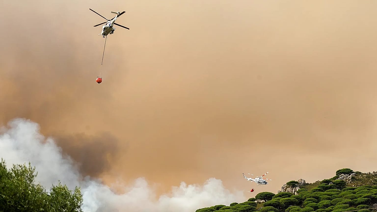 Firefighting helicopters drop water to extinguish a blaze in Torre de la Peña, southern Spain, August 2025. 