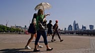A woman holds an umbrella to shelter from the sun, as she walks on the south bank of river Thames, in London, Monday, July 18, 2022. 