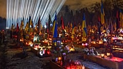 Flutlichter leuchten über den Gräbern der gefallenen Soldaten, während die Menschen am Vorabend des vierten Jahrestages der russischen Invasion in Lemberg Kerzen anzünden, 23. Februar 2026.