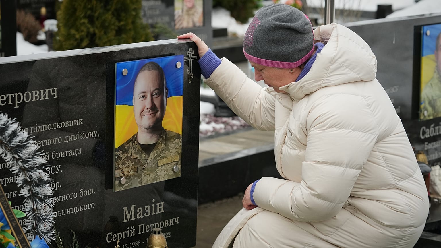 Una donna siede davanti alla tomba di un suo parente durante la commemorazione dei soldati ucraini caduti a Bucha, Ucraina, 24 febbraio 2026. 