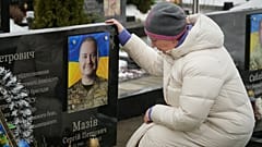 Eine Frau sitzt vor dem Grab ihres Verwandten während einer Gedenkfeier für gefallene ukrainische Soldaten in Bucha, Ukraine, 24. Februar 2026. 