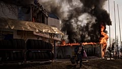 Um homem recupera artigos de uma loja que se incendiou durante um ataque russo em Kharkiv, na Ucrânia, na sexta-feira, 25 de março de 2022.