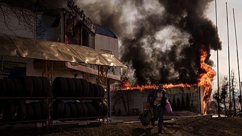 A man recovers items from a shop that caught fire in a Russian attack in Kharkiv, Ukraine, Friday, March 25, 2022.