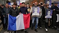 Des personnes participent à une marche avec des drapeaux nationaux français et des portraits de l'étudiant assassiné à Lyon, en France, samedi 21 février.