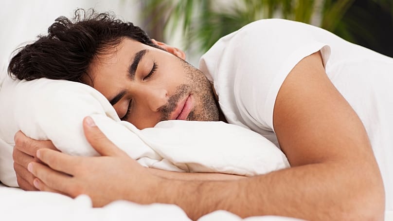 رجل مستلقٍ على جانبه ويحتضن الوسادة.