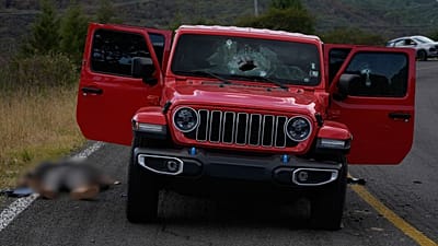 Un cuerpo yace junto a un vehículo acribillado a balazos en Tapalpa, México, el lunes 23 de febrero de 2026 (Foto AP/Marco Ugarte)
