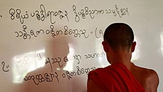 In this photo taken Thursday, Jan. 19, 2012, a Karen Buddhist monk writes Karen scripts on a white board while teaching at a classroom