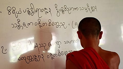 In this photo taken Thursday, Jan. 19, 2012, a Karen Buddhist monk writes Karen scripts on a white board while teaching at a classroom