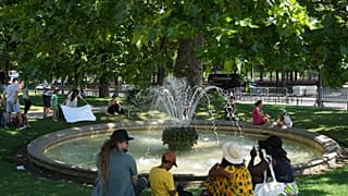  Des personnes sont assises autour d'une fontaine dans le jardin des Tuileries, mardi 1er juillet 2025 à Paris, en pleine vague de chaleur. (Photo AP/Christophe Ena)