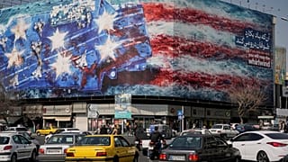 لوحة إعلانية تصور حاملة طائرات أمريكية عليها طائرات مقاتلة متضررة على سطحها، في ساحة انقلاب إسلامي (الثورة الإسلامية) في طهران، إيران، يوم الأحد 22 فبراير 2026.