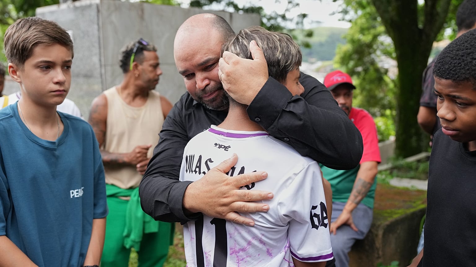 Le père de la victime de 11 ans des fortes pluies et inondations est réconforté par les amis de son fils lors des funérailles et de l'enterrement à Juiz de Fora